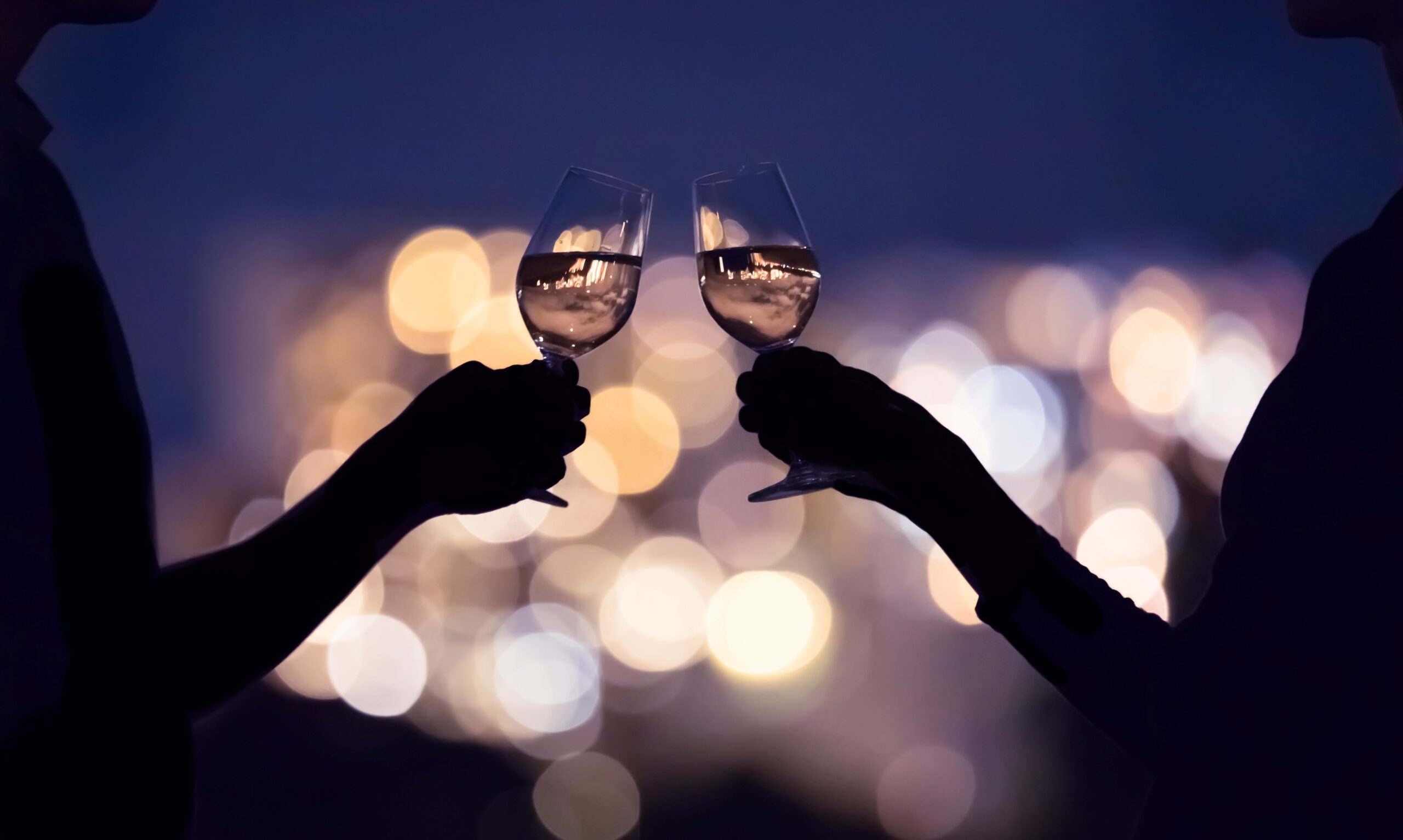 Zwei Personen stoßen mit einem Glas Wein an 